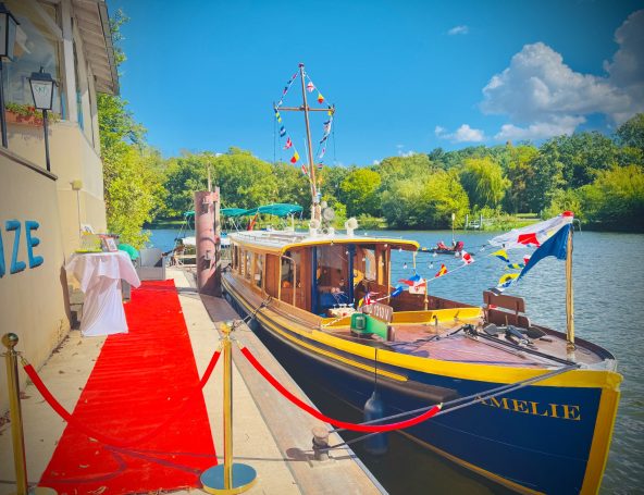 Ein hölzernes Boot am Ufer mit rotem Teppich und festlicher Dekoration.